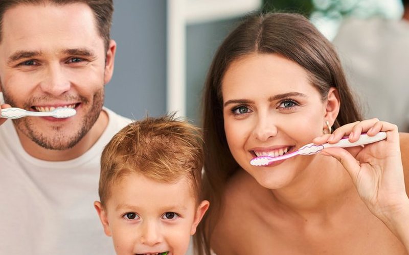 A family smiling together while brushing