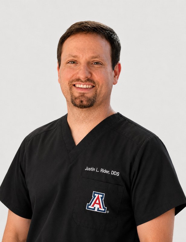 Dr. Justin Rider, DDS, smiling in black scrubs
